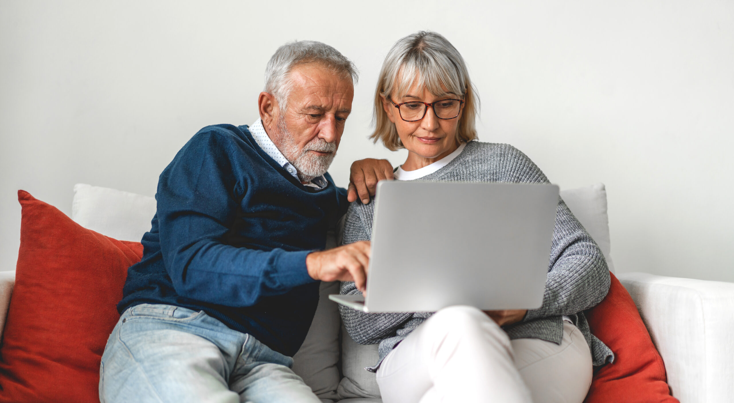 senior couple family having good time using laptop computer together.happy elderly husband and wife checking social media and reading news or shopping online while sitting on sofa at home